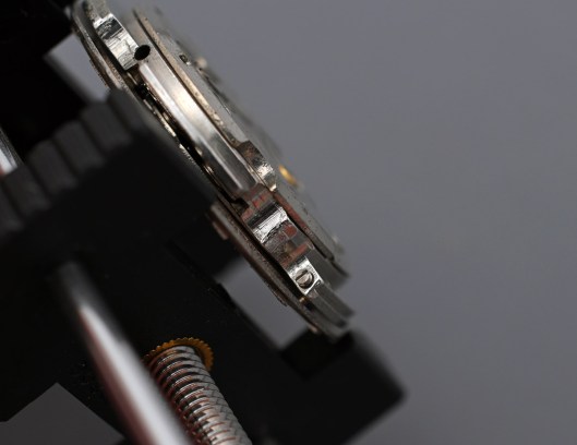 A side view of the movement showing one dial foot screw