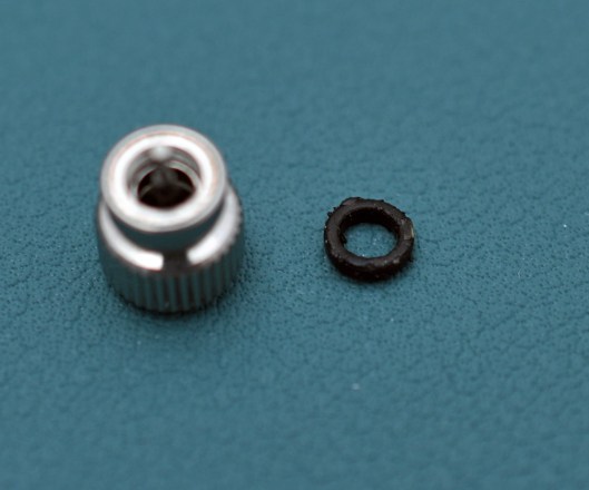 A close-up of the worn crown gasket removed from the crown, also in shot