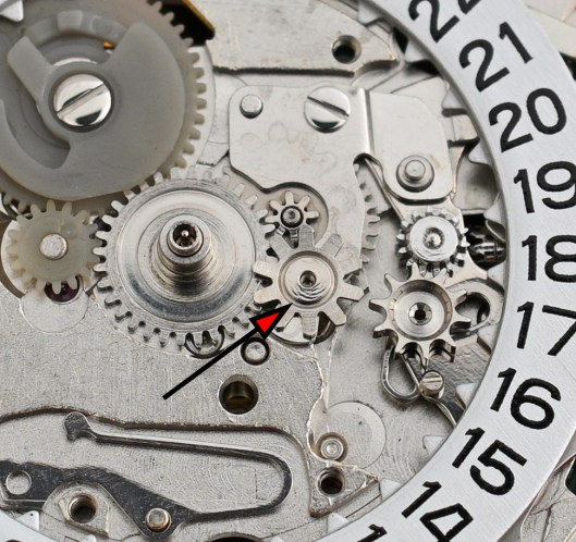 A close-up of the calendar side with an arrow indicating the postion of the day corrector intermediate wheel